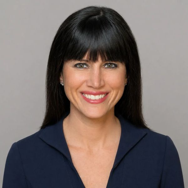 Smiling woman with black hair and bangs wearing a navy blue top.