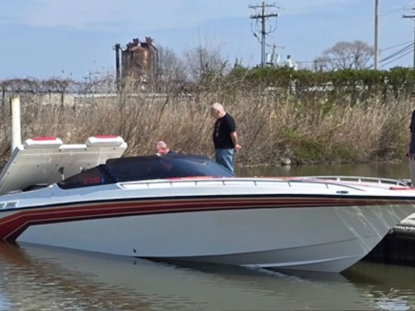 A sleek white and red speedboat docked with two men nearby.