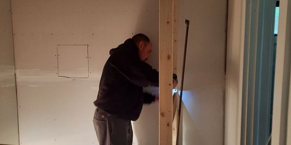 Man installing drywall inside a building under construction.