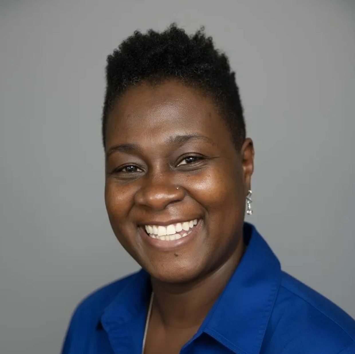 Smiling woman in a blue shirt against a plain background.