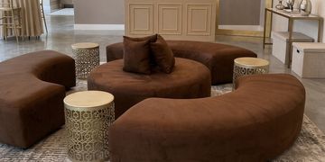 furniture rental package consisting of 3 curved benches, one round ottoman, three tables and pillows