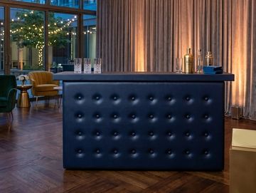 Black tufted bar in the middle of a venue 