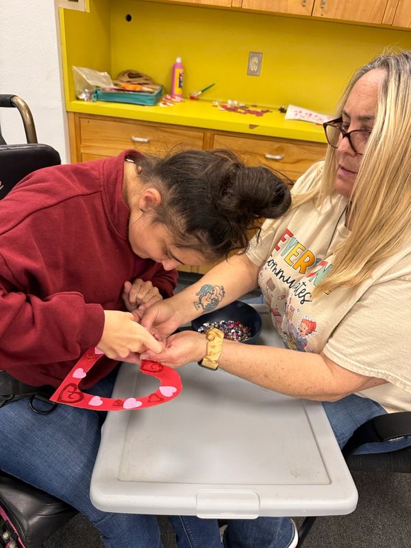 Two women bonding over a heart-shaped craft.
