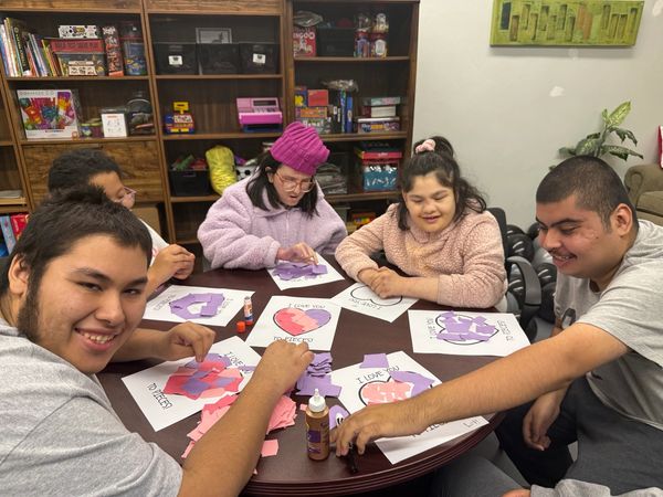 Group of people making heart crafts at table.