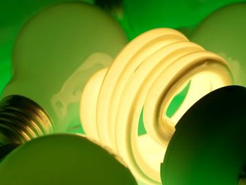 Close-up of glowing spiral compact fluorescent light bulb among other bulbs.
