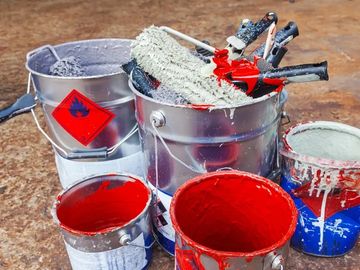 Buckets of red and white paint with rollers and brushes.