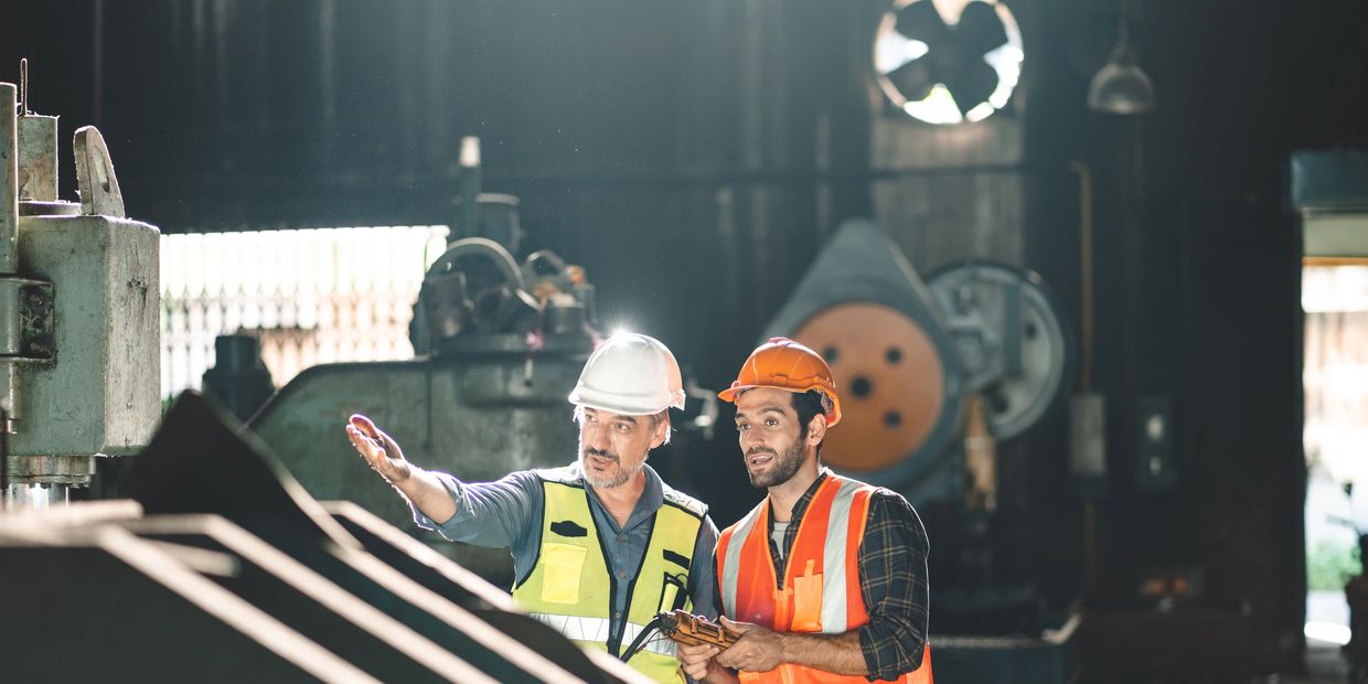 Two workers in safety gear discussing at an industrial site.
