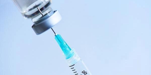 Syringe drawing vaccine from a vial.