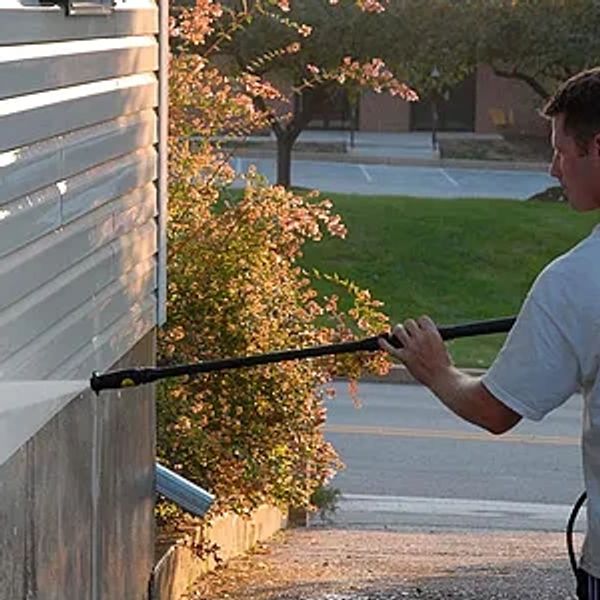 Person pressure washing the side of a building.