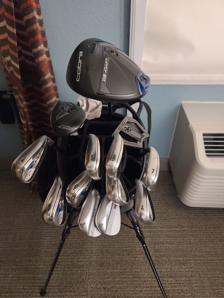 Set of golf clubs neatly organized in a stand indoors.
