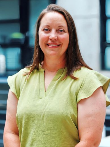 Smiling woman in a light green blouse posing indoors.