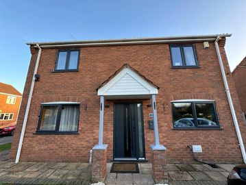 Modern brick house with black-framed windows and a central black door under a small porch.