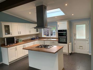 Modern kitchen with white cabinets, wooden countertops, and a central island with a gas stove.