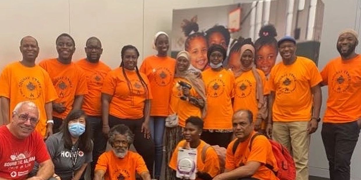 Group of people in orange shirts posing indoors.