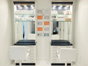 Modern beauty salon stations with white chairs and black countertops.