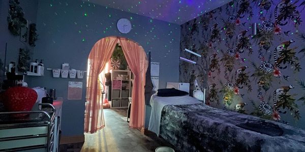 Cozy therapy or massage room with soft lighting and floral wallpaper.