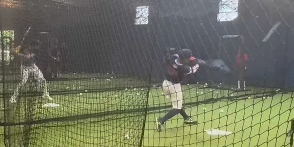 Indoor baseball batting practice at LIB camp with players ready to hit.