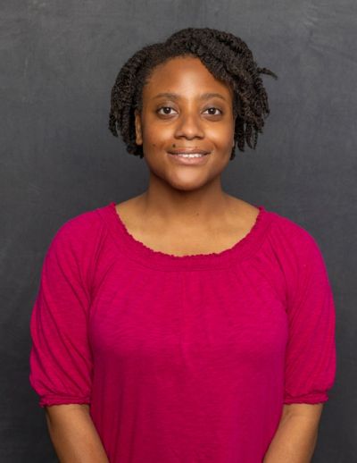 Smiling woman in a red top with textured hair.