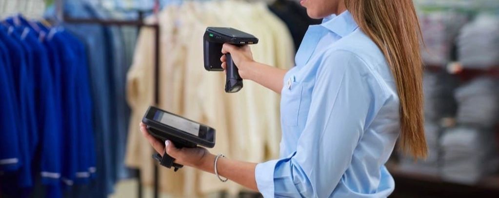 Retail worker scanning clothes with barcode scanner in store.