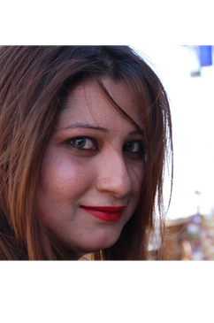 Close-up of a woman smiling with red lipstick and brown hair.