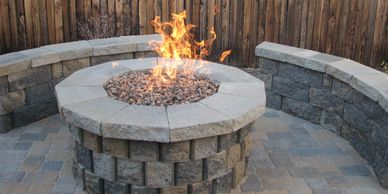 Stone fire pit with flames and curved stone seating.