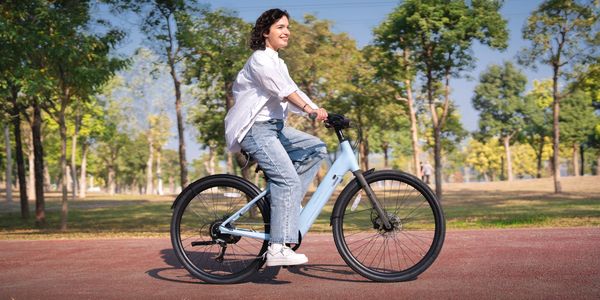 A woman enjoys a bike ride in a sunny park.