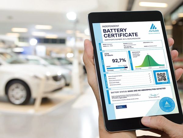 Person holding a tablet displaying an independent battery certificate for a Volkswagen car.
