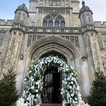 A stunning balloon-floral arch adorns a grand entrance. Ivory balloons blend with white blooms and g