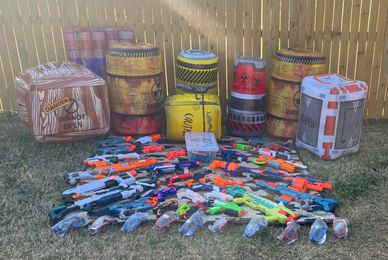 A collection of toy dart guns and inflatable barrels outdoors.