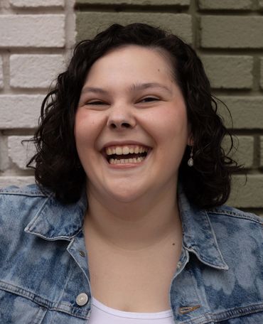 A cheerful woman with curly hair laughing joyfully.