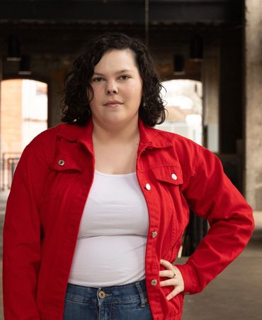 Confident woman wearing a red jacket and white top indoors.