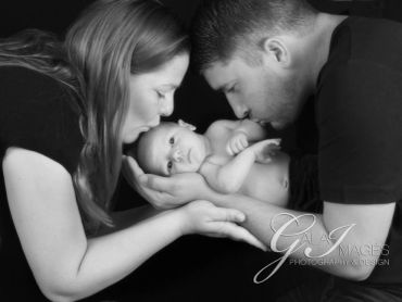 Black and white photo of parents lovingly holding their newborn baby.