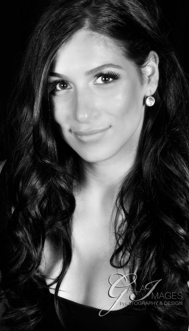 Black and white portrait of a smiling woman with long wavy hair and earrings.