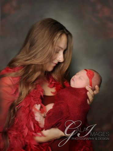 Mother tenderly holds newborn baby wrapped in red.