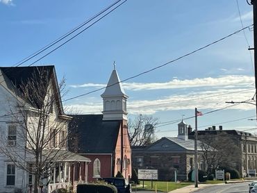 A church with a steeple and clock on it's side.