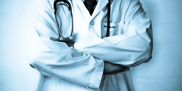 A doctor in a white coat with a stethoscope stands confidently, reflecting expertise in patient care.