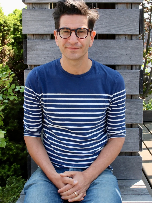 Andrew Gardner smiles, sitting on a wooden bench