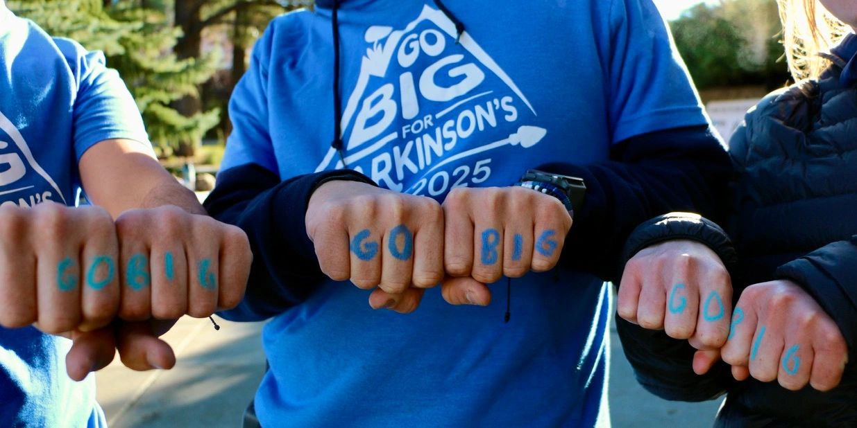 Hands with "GO BIG" written on knuckles, promoting Parkinson's 2025.