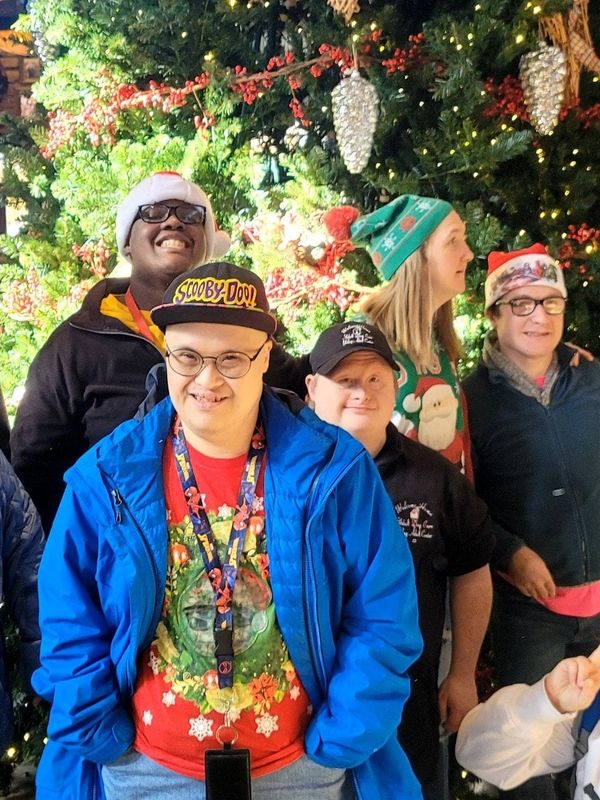 A group of smiling people posing in front of a decorated Christmas tree.