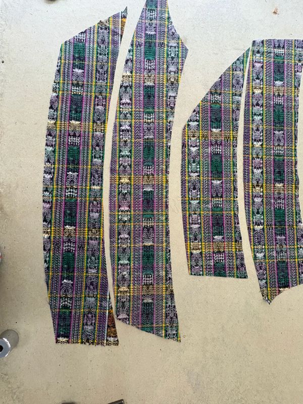 Cut fabric pieces with a colorful plaid pattern laid out for sewing.