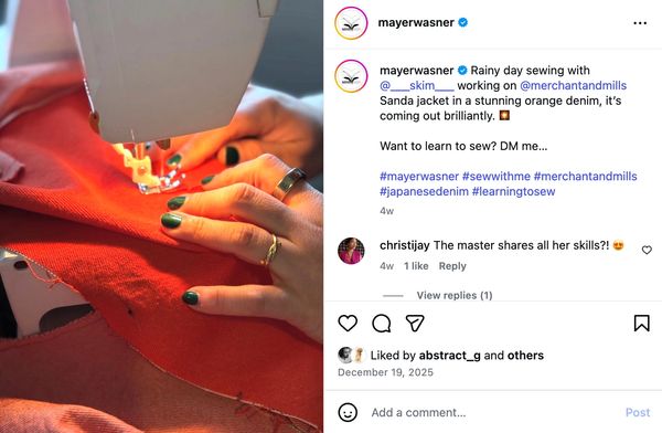 Close-up of hands sewing orange denim fabric on a sewing machine.