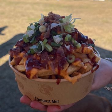 Loaded fries with toppings in a compostable container.