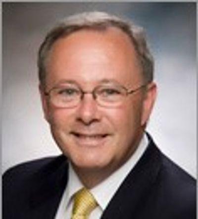 Professional man wearing glasses and a suit with a yellow tie.