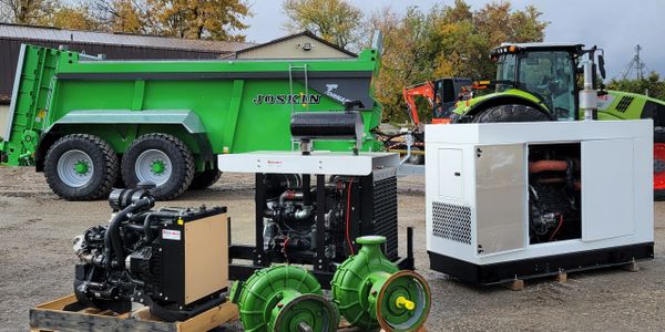 Various industrial machines and a green Joskin trailer outdoors.