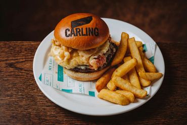 Burger with fries on a white plate on a wooden table.