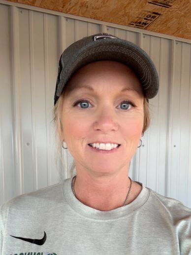 Smiling woman wearing a gray cap and sweatshirt indoors.