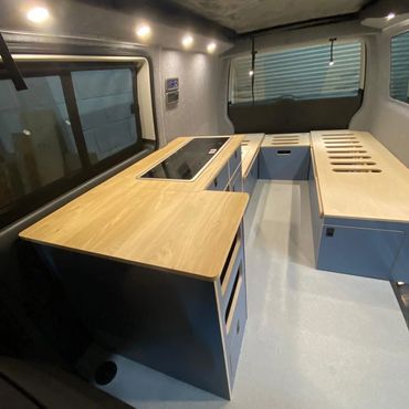 Interior of a sleek, modern camper van kitchen and seating area.