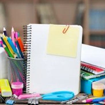Notebook with sticky note surrounded by stationery.