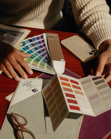 Woman looking at color swatches in Pantone book with readers and iPhone.