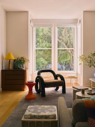 Modern living room with unique chair and large window.